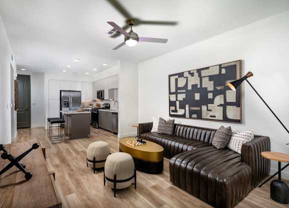A living room with a brown leather couch and a ceiling fan.