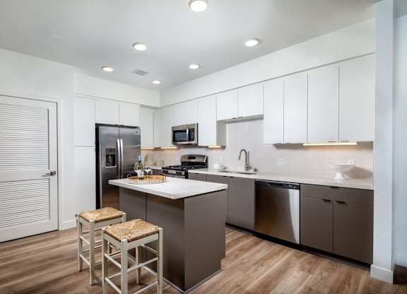 A kitchen with a refrigerator, microwave, and a sink.