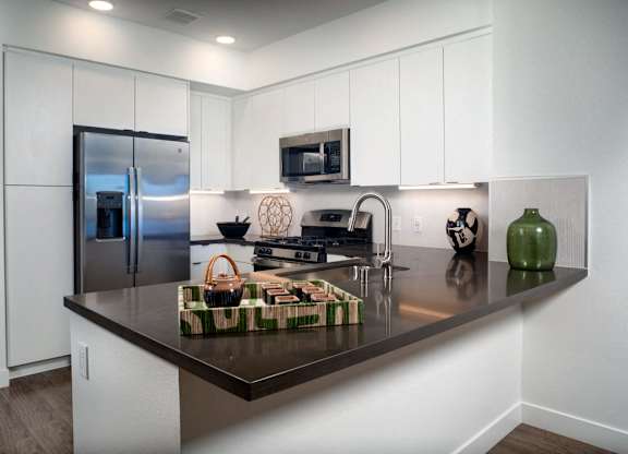 A kitchen with a black counter top and white cabinets.