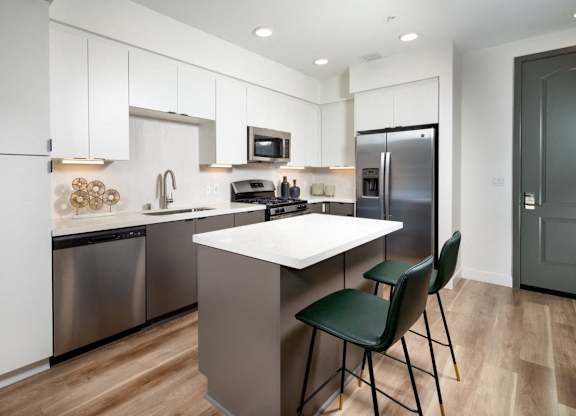 A modern kitchen with a white island and stainless steel appliances.
