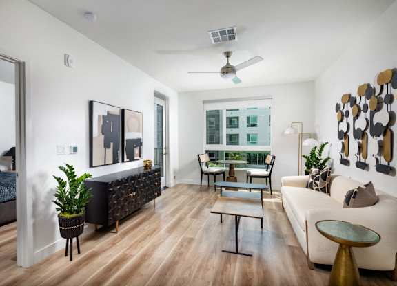 A living room with a black couch, a white couch, a coffee table, and a ceiling fan.