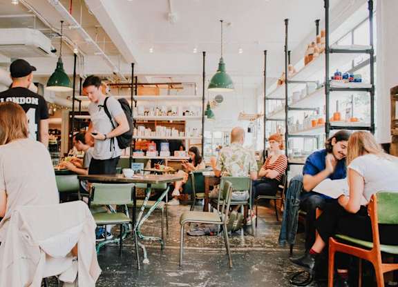 A group of people are sitting and standing in a restaurant.