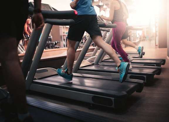 A group of people are exercising on treadmills in a gym.