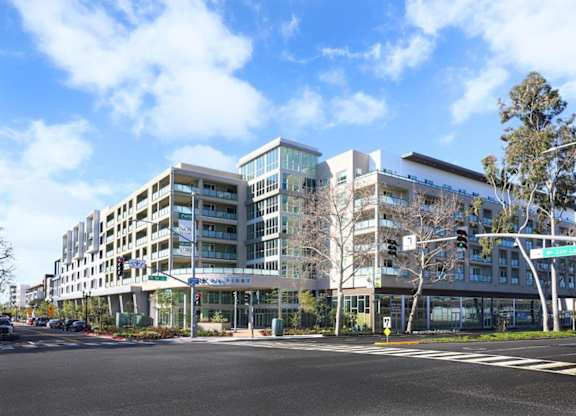 A modern building with a glass facade is located on a street corner.