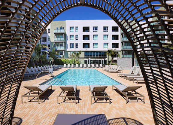A pool surrounded by chairs and a wooden structure.