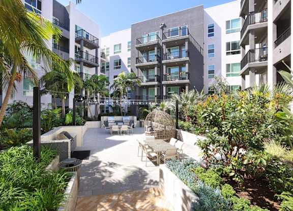 A courtyard surrounded by buildings with a white fence and plants.
