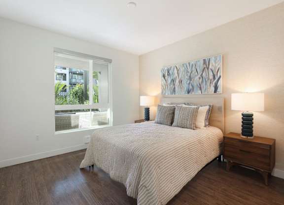 A bedroom with a bed, nightstand, and a painting on the wall.