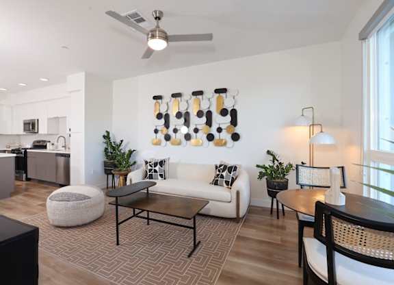 A modern living room with a white couch, a coffee table, and a ceiling fan.