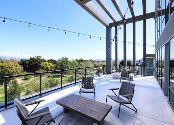 A patio with chairs and a table overlooking a green landscape.