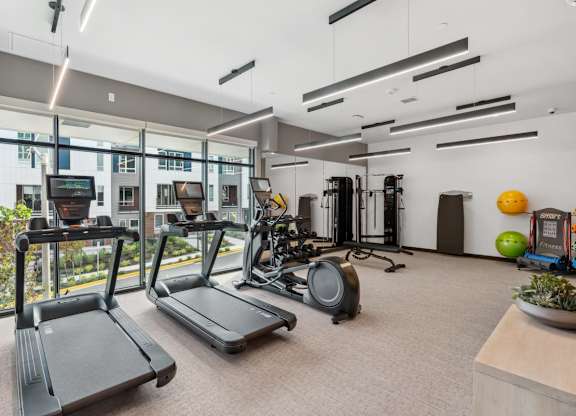 A gym with treadmills, exercise equipment, and a bowl of fruit at Cru at Willows Apartments, Redmond, Washington