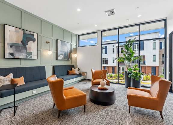 A modern living room with a grey sofa, orange chairs, and a coffee table at Cru at Willows Apartments, Washington