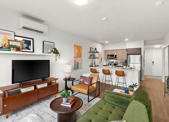 A living room with a green couch and a wooden entertainment center at Cru at Willows Apartments, Redmond, WA