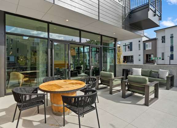 A patio with a table and chairs is shown at Cru at Willows Apartments, Redmond