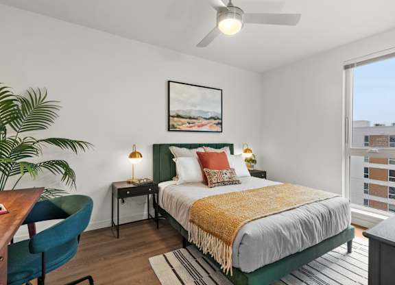 A bedroom with a bed, a chair, a desk, and a ceiling fan at Cru at Willows Apartments, Redmond