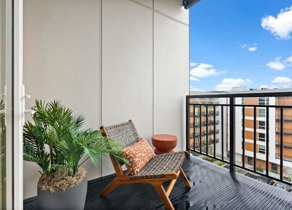 A balcony with a chair, potted plant, and a cushion at Cru at Willows Apartments, Redmond, Washington