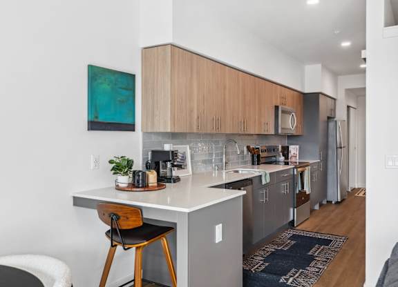 A kitchen with a white countertop and wooden cabinets at Cru at Willows Apartments, Washington
