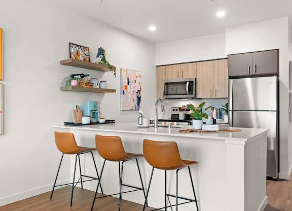 A kitchen with a white countertop and orange chairs at Cru at Willows Apartments, Redmond, WA
