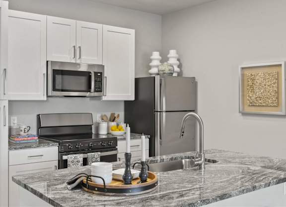 A kitchen with a marble countertop and stainless steel appliances.