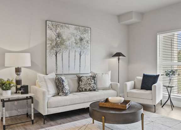 A living room with a white couch, a coffee table, and a painting on the wall.