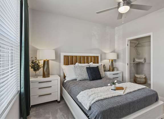 A bedroom with a bed, nightstands, and a ceiling fan.