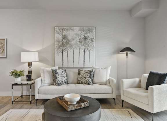 A living room with a white couch, a grey coffee table, and a painting on the wall.