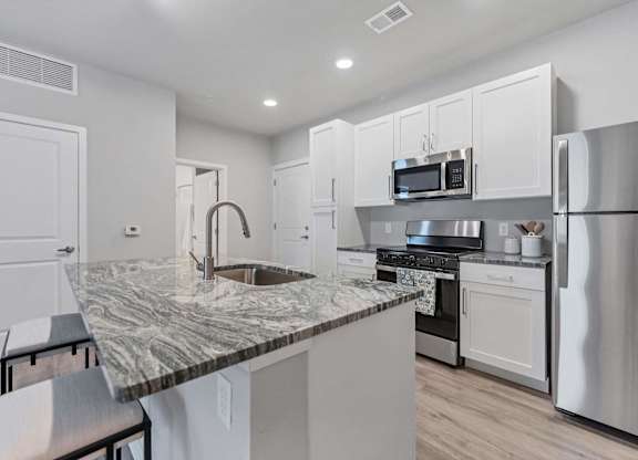 A kitchen with a marble countertop and stainless steel appliances.