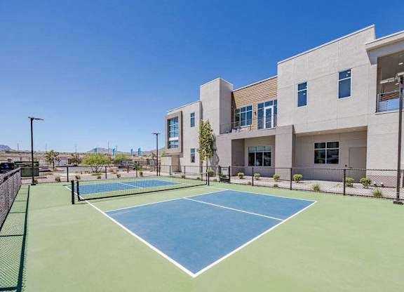 A tennis court is located in front of a modern building.