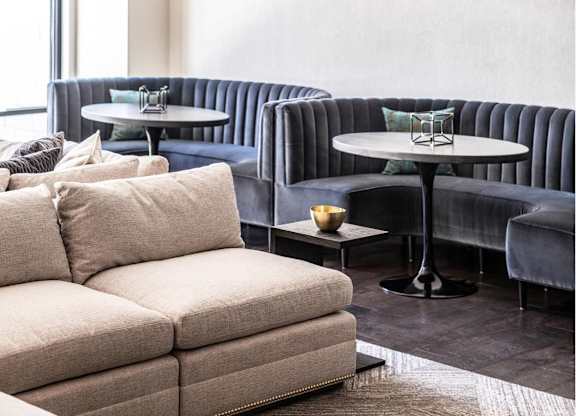 A modern living room with a large sofa, a round table, and a hanging light fixture.