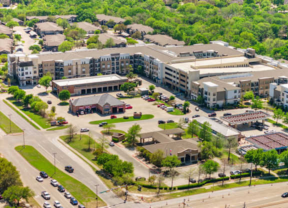 A large apartment complex with a parking lot in front.