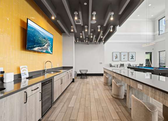 A modern kitchen with a long counter and a painting hanging above it.