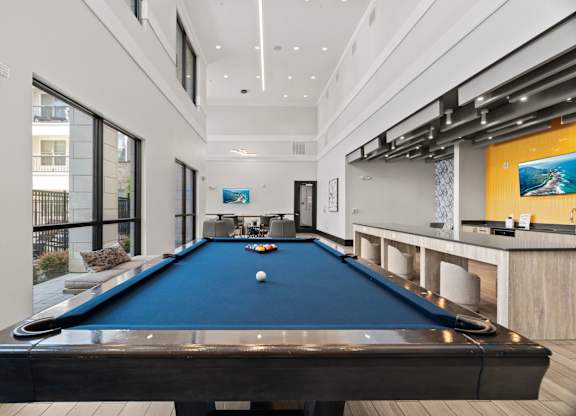 A pool table in a room with a bar area.