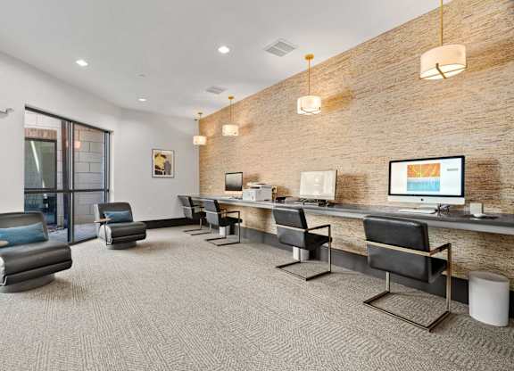 A modern office space with a brick wall and a long desk with chairs.