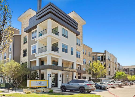 A modern apartment building with a leasing sign in front.