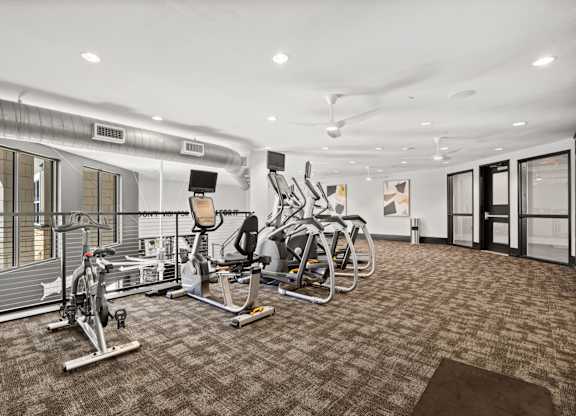 A gym with a variety of exercise equipment including treadmills, stationary bikes, and weight machines.