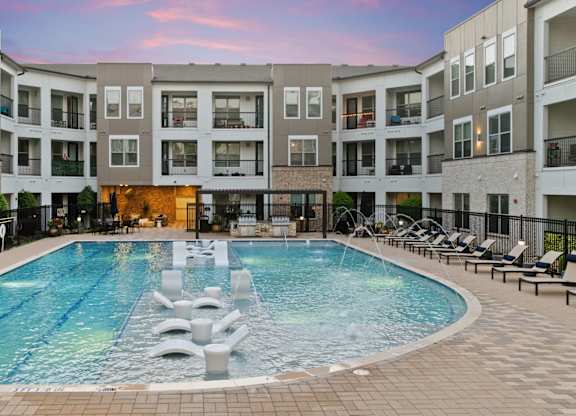 A large swimming pool in the middle of a courtyard surrounded by apartment buildings.