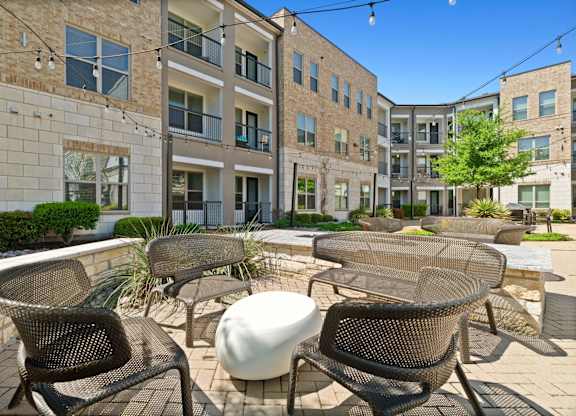 A patio with chairs and a table in front of a building.