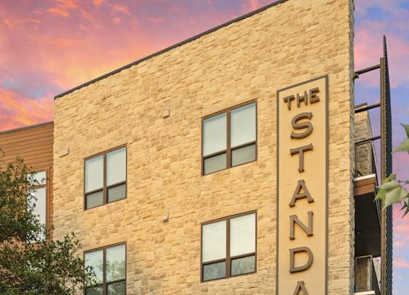 The Standard building has a brick facade and is surrounded by a landscaped area.
