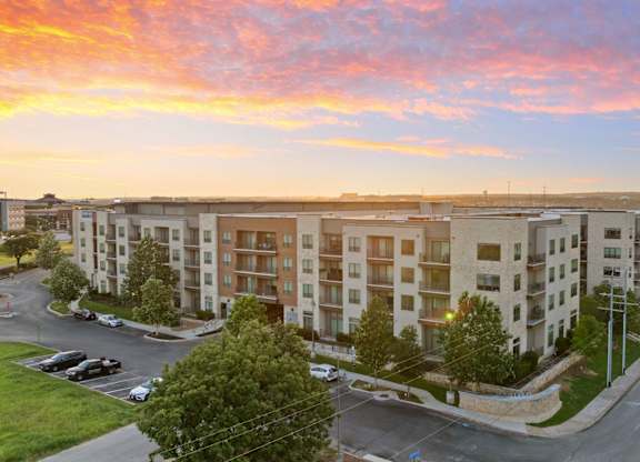 A sunset view of a street with apartment buildings on the side.