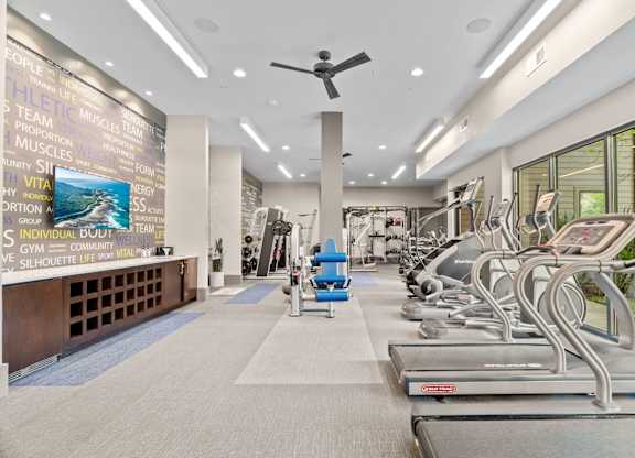 A gym with treadmills and a wall of motivational words.