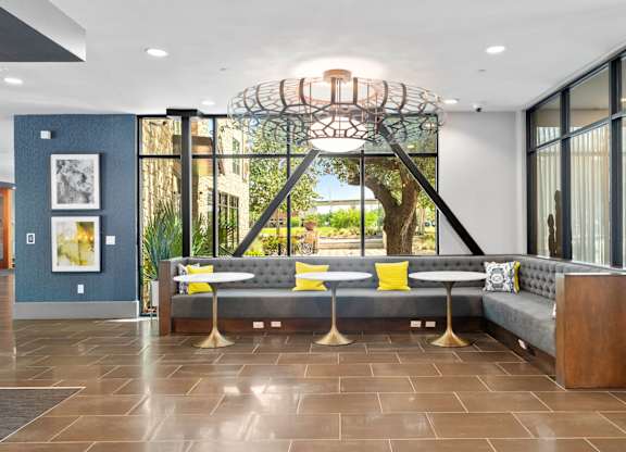 A modern living room with a grey sofa and a large window.