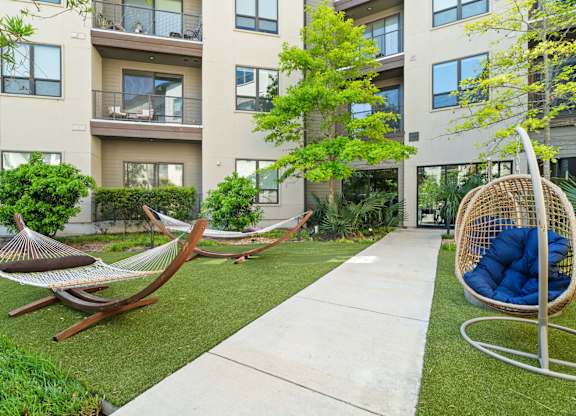 A modern outdoor patio area with a hammock and a swing.