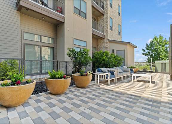 A patio with a checkered floor and three large planters.