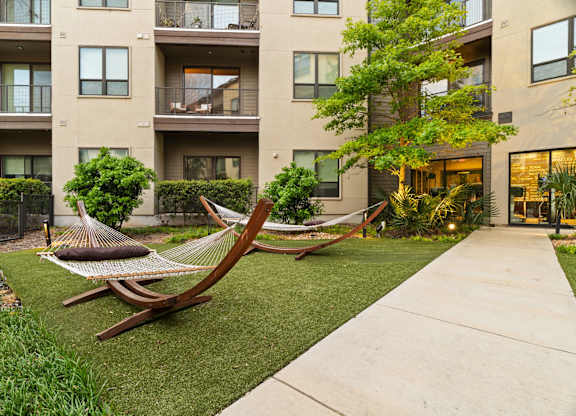 A hammock is placed in the front yard of a building.