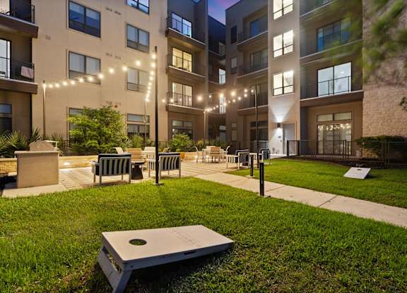 A modern apartment complex with a grassy courtyard and benches.