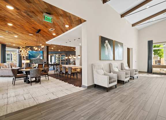 A room with a wooden ceiling and floor, a white couch, and a painting on the wall.