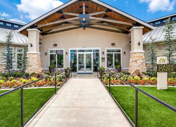The image shows the front of a leasing center with a clear blue sky in the background.