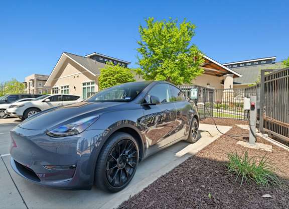 A grey Tesla Model 3 is parked in a parking lot.