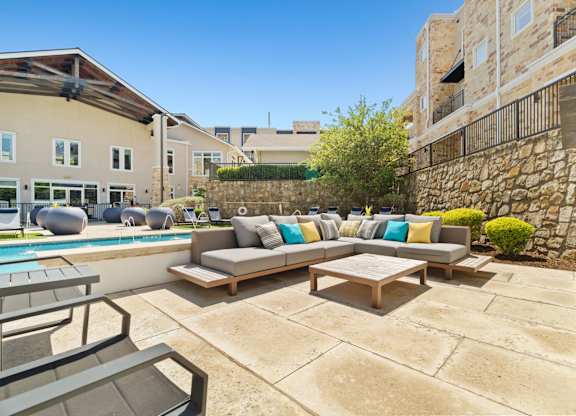 A patio with a couch and chairs overlooking a pool.