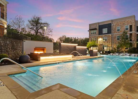 A swimming pool with a waterfall and a fireplace in the background.