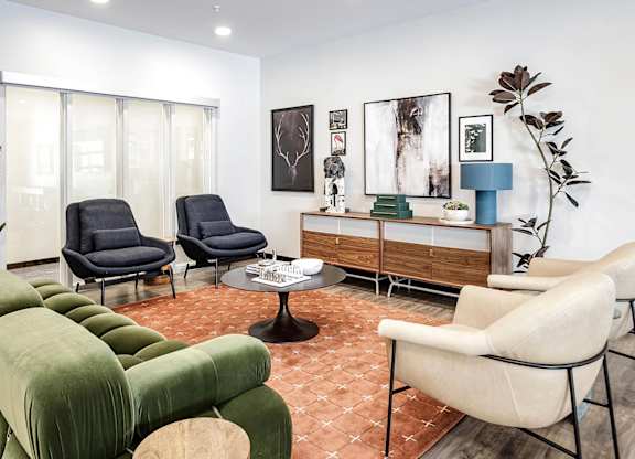 A living room with a green sofa, two black chairs, and a white chair.